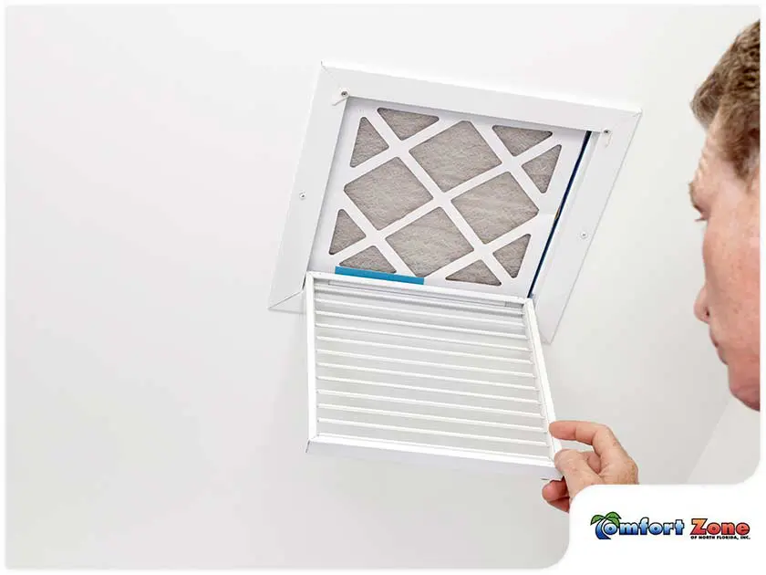 AC Repairman Opening Air Filter in Ceiling An AC repairman is opening up an air filter in the ceiling, preparing to clean or replace it for better airflow and system efficiency
