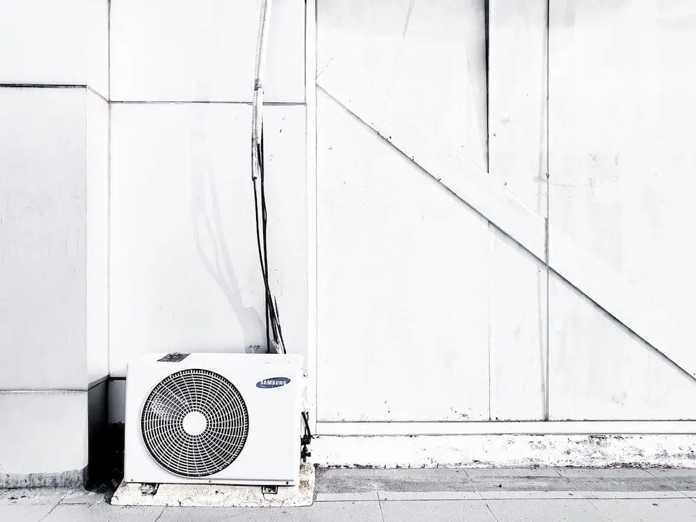 Frozen Air Conditioner Outside of a Building A white frozen air conditioner is sitting outside of a building, likely due to ice buildup or low temperatures affecting its operation