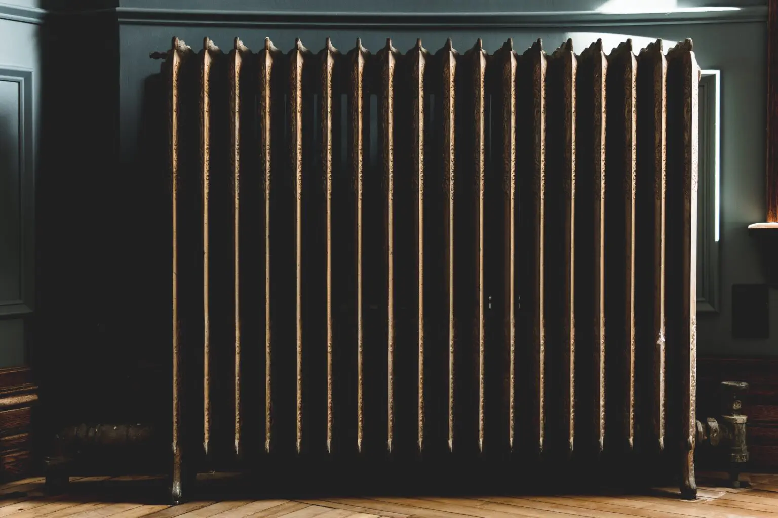 Radiator in Front of a Wall Text: A radiator is positioned in front of a wall, typically used for heating a room and maintaining warmth