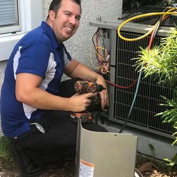 An HVAC repair technician is fixing the wires on an commercial air conditioner, ensuring proper electrical connections for functionality