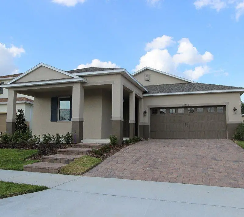 A house with two garage doors and brick driveway.