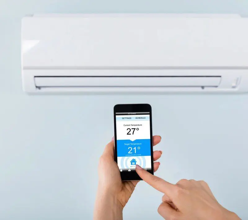 A person is using their phone to control the temperature of an air conditioner.