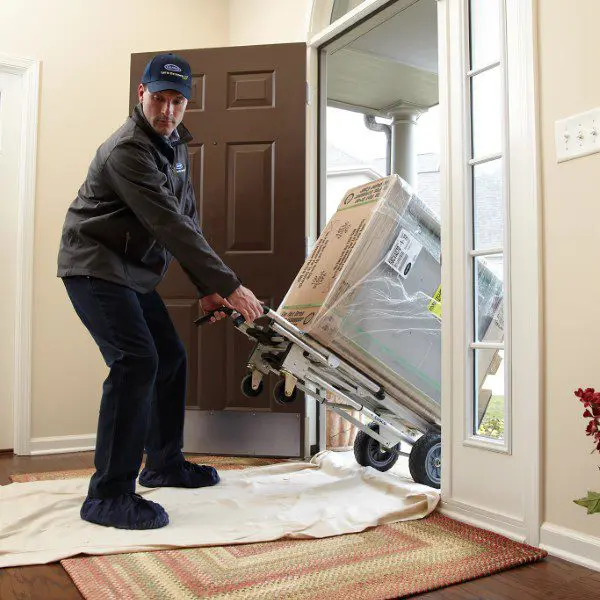 An HVAC installer is relocating an AC unit in Yulee, carefully moving the unit to a new location for optimal performance