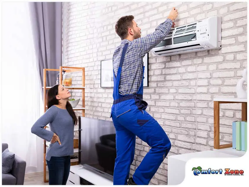 Ductless contractor services A AC repairman is installing a ductless mini split air conditioning unit while the homeowner points out the spot for proper placement