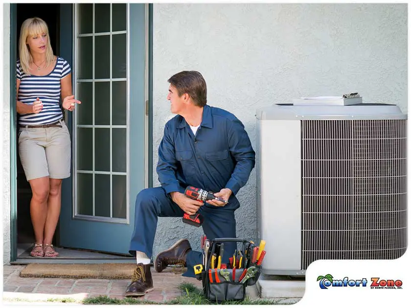 e6b20faf5f7991aa4780b05a02b32a49b2a23531-lady-homeowner-discussing-with-hvac-technician An AC repairman is sitting on the ground next to an air conditioner in Jacksonville, Florida, discussing repair options with a homeowner to resolve the issue.