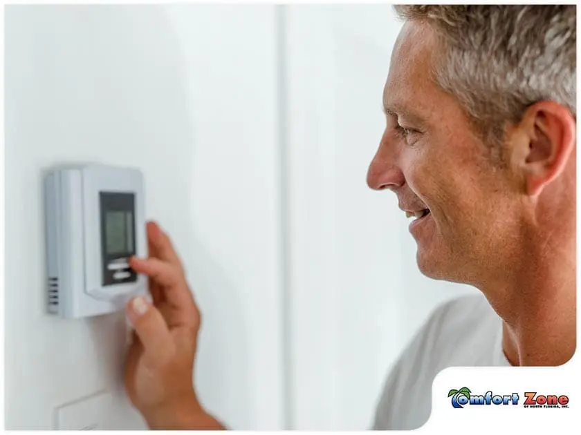 AC Service Technician Smiling While Looking at Thermostat An AC service technician is smiling while looking at the thermostat, ensuring the system is set to the desired temperature