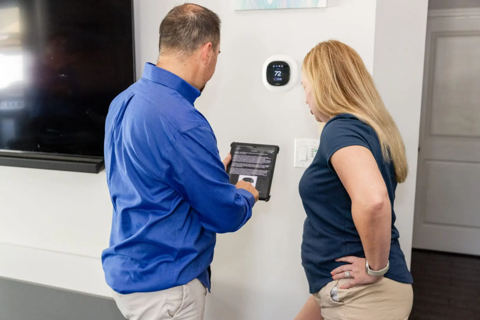 A HVAC consultant and customer are looking at an electronic device WIFI tablet.