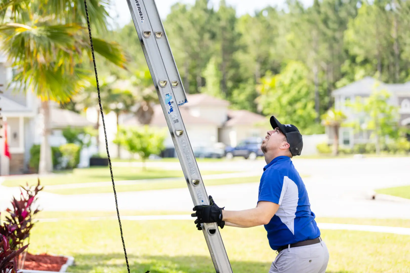 A HVAC Service Technician holding onto a ladder to reach the top of a house to make a ventilation repair on a exhaust system.