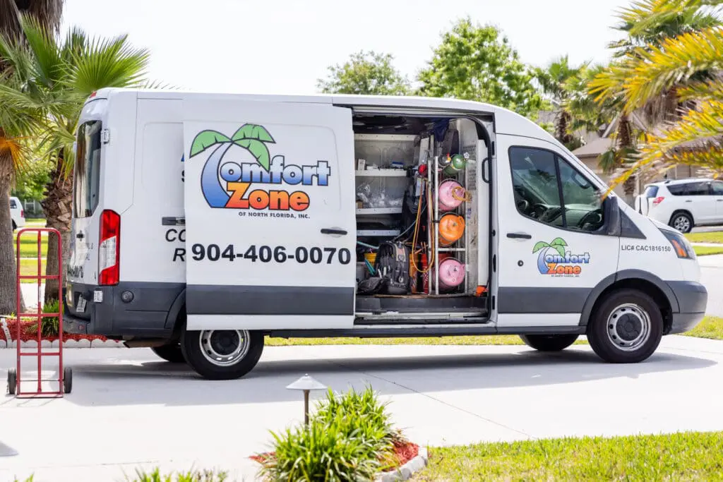 A white Comfort Zone of North Florida heating and Cooling Service van with palm trees in the back.