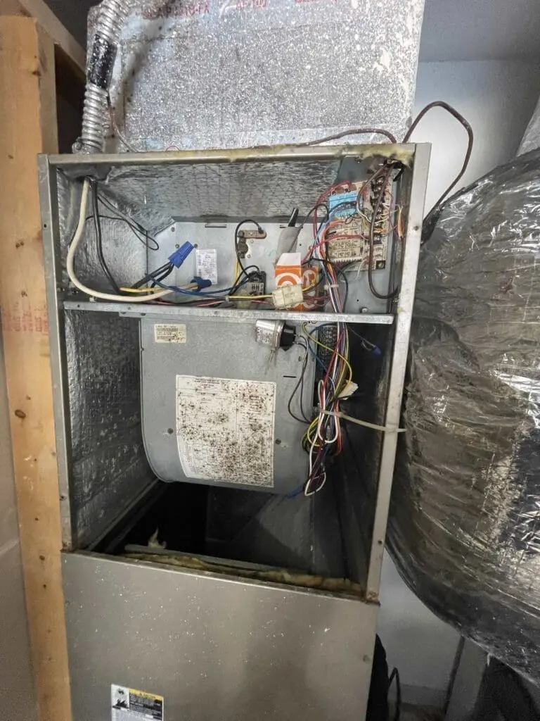 Air conditioning air handler located in a garage with ductwork and electrical wiring.