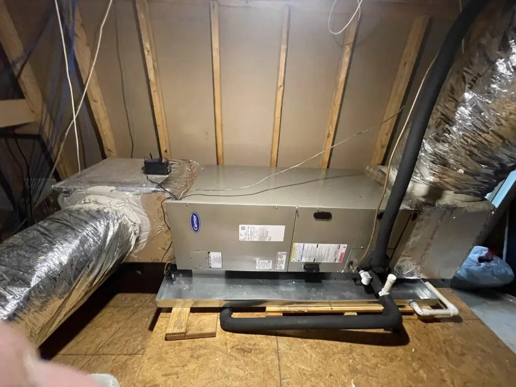 A Air Handler located in an attic laying on its side sitting in a condensate drain pan.