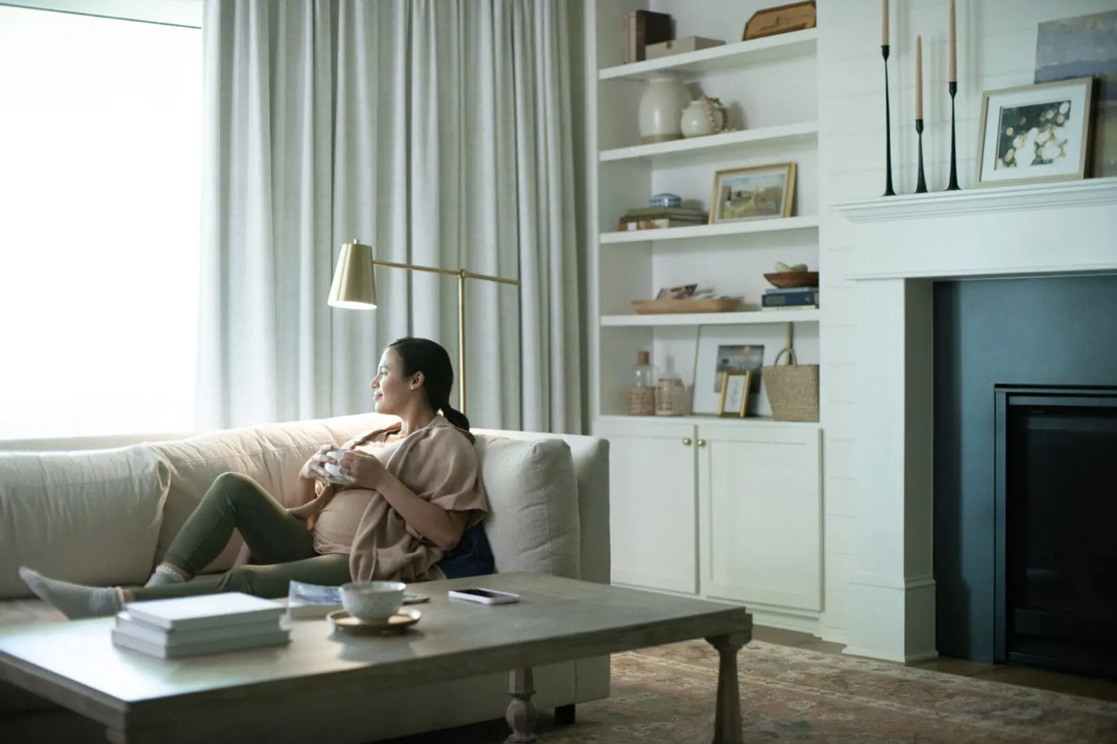 Lady laying on a couch while enjoying coffee in the air conditioned temperature controlled living room