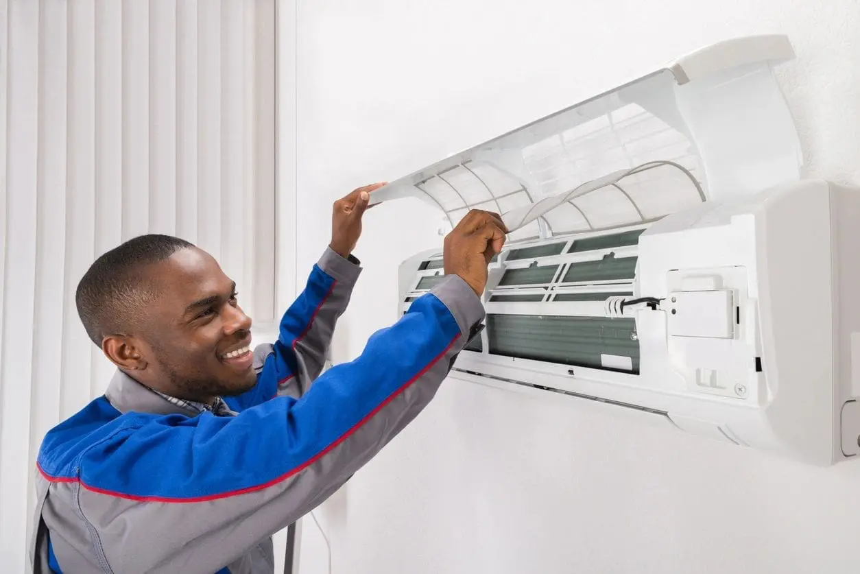 Air Conditioning service technician working on a ductless mini split repair that is hanging on a white wall