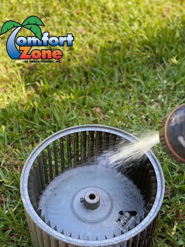 AC tech cleaning the blower wheel to improve airflow and efficiency in an air conditioning unit for better performance.