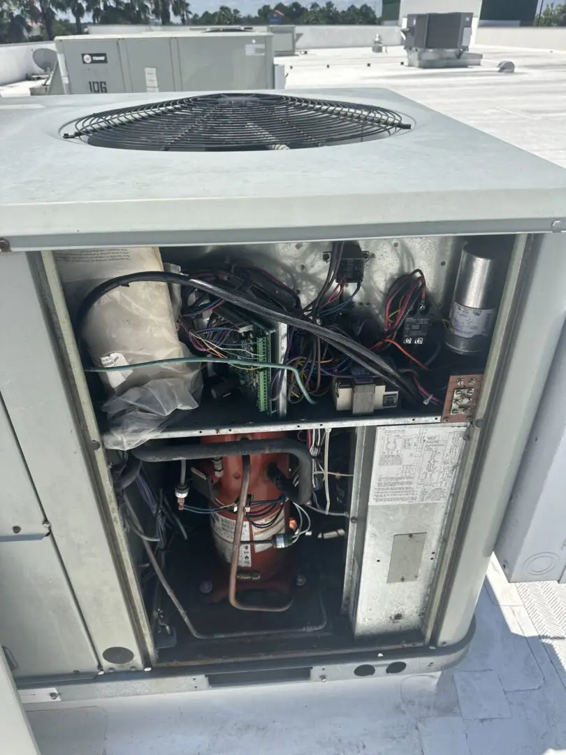 A technician inspects the internal components of an outdoor unit during a standard HVAC contractor visit.