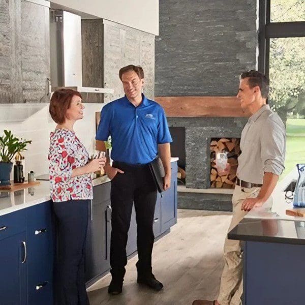 A group of people standing in a kitchen talking.