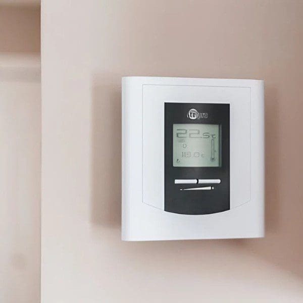 A white wall mounted thermostat on the side of a room.