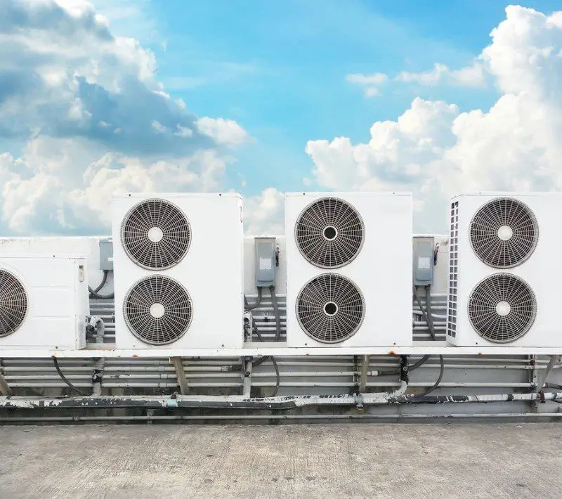 A row of air conditioners sitting on top of a building.