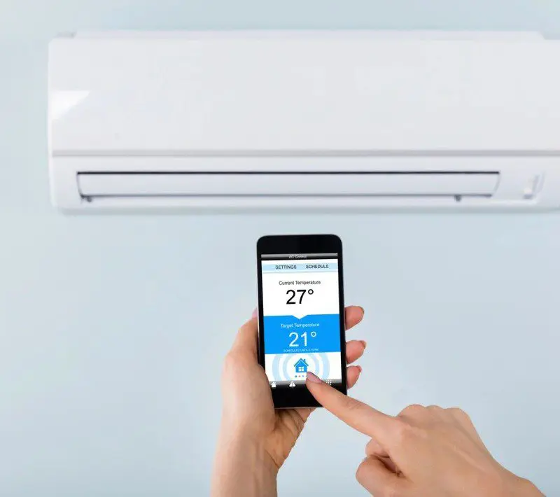 A hand holding a smartphone to control the air conditioner.