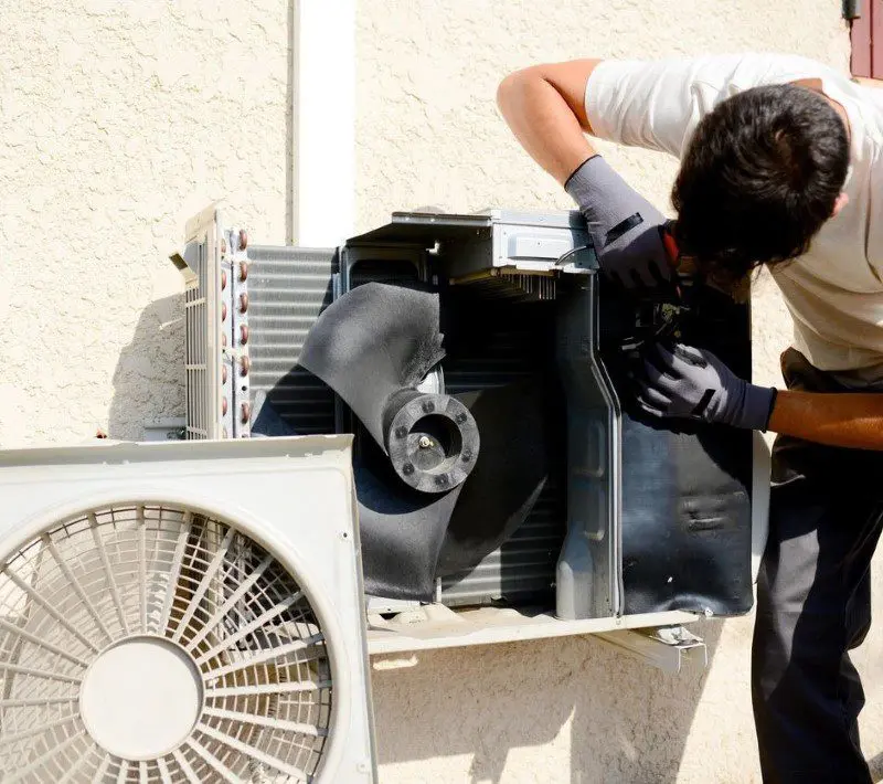 A technician repairs an air conditioning unit.