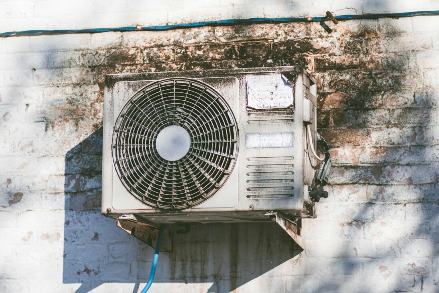 An old air conditioning unit mounted on a weathered wall with visible stains and peeling paint.