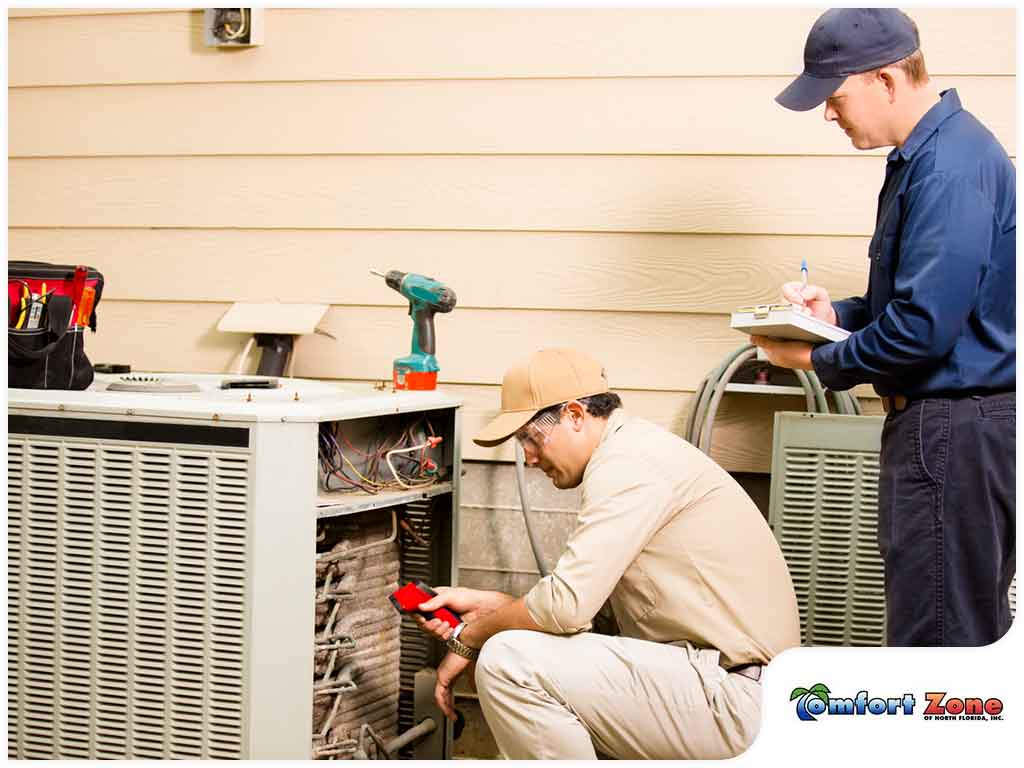 Two men working on an air conditioner unit.