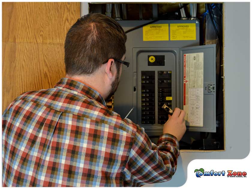 A man is working on an electrical panel.