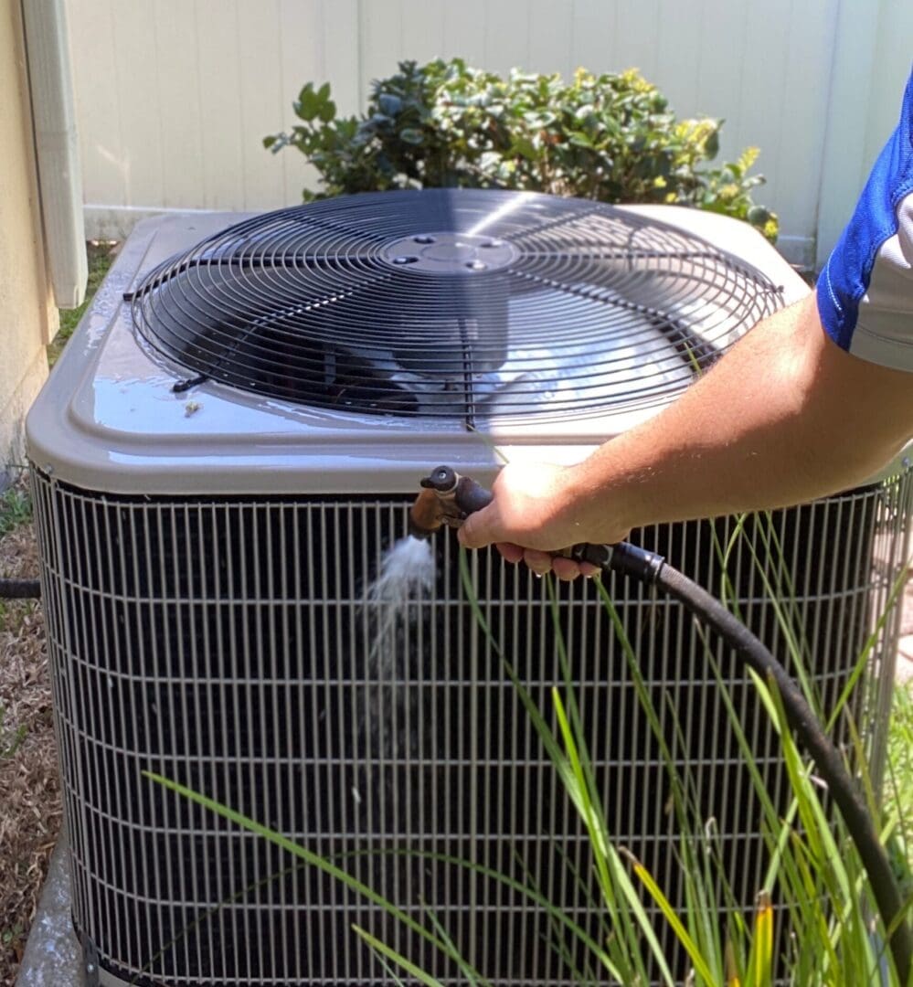 A technician cleaning a residential ac unit with a high-pressure water spray.