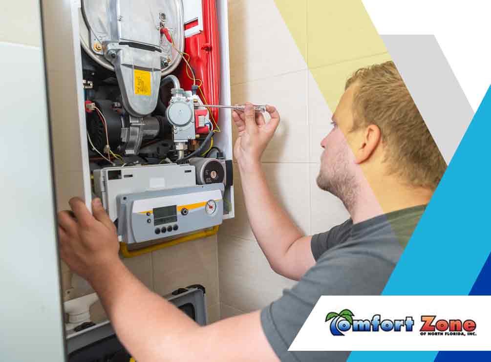 A technician repairing a gas boiler while using a screwdriver, with the company logo "comfort zone" visible in the corner.
