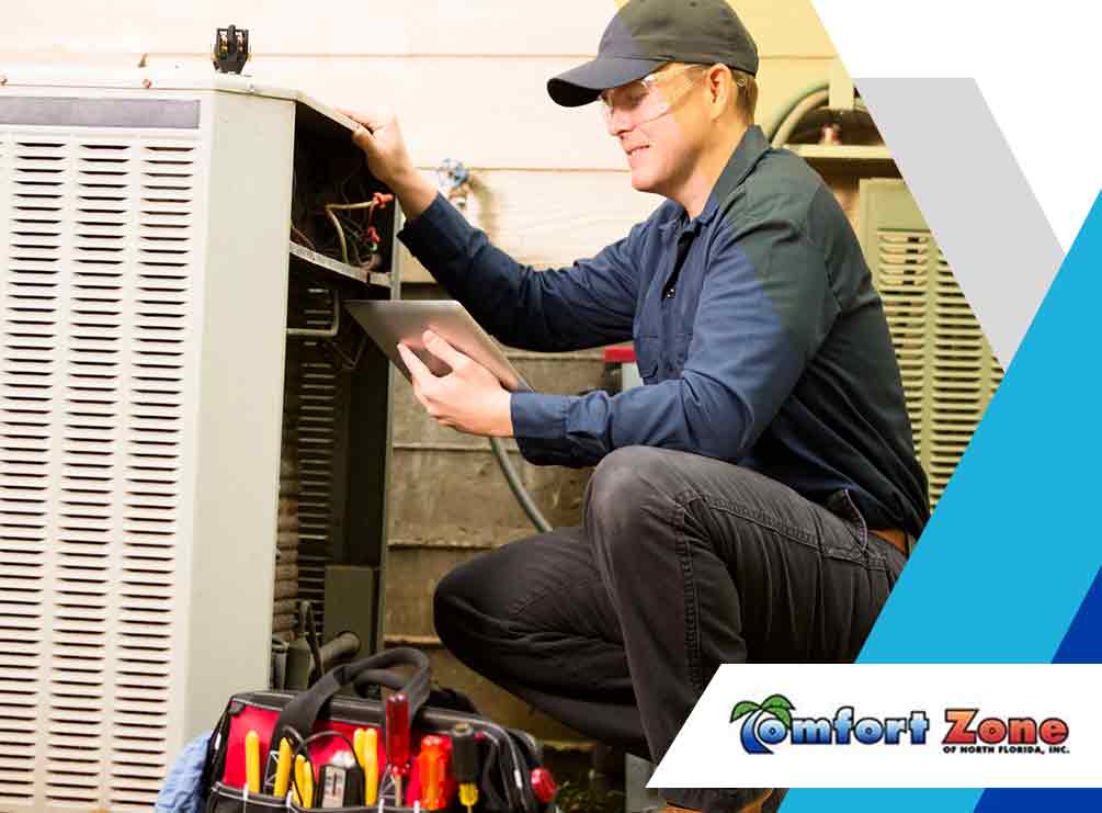 A technician using a tablet while repairing an hvac unit, with tools nearby and a company logo "comfort zone" visible.