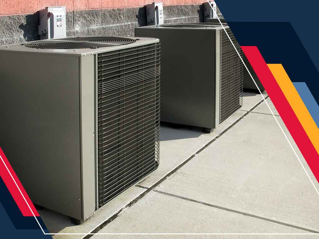 Two large commercial hvac units installed on a concrete pad beside a building, with a geometric abstract design overlay in red, yellow, and blue.