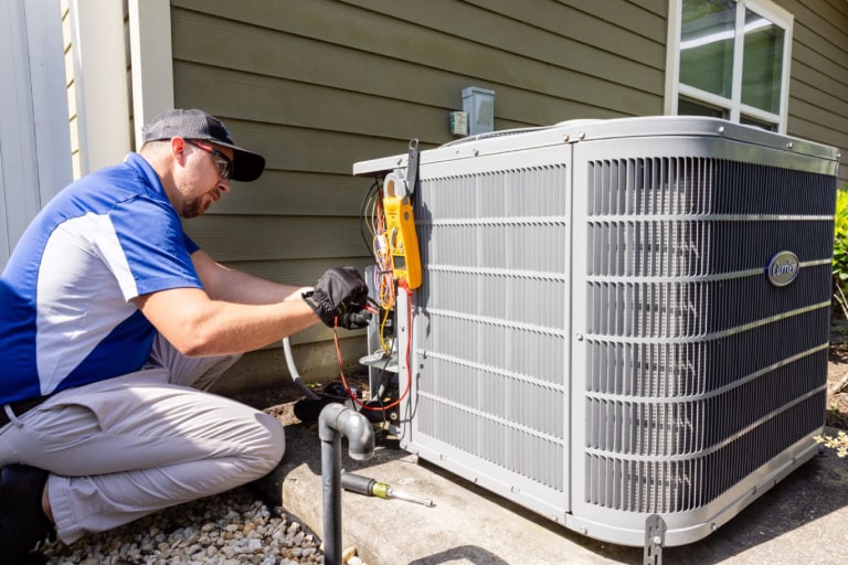 AC technician servicing a condenser unit during a repair visit