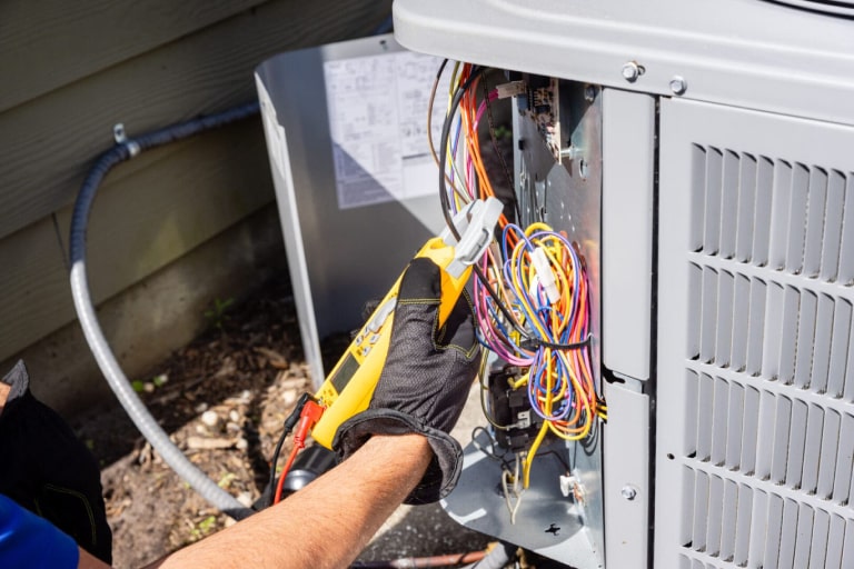 Air Conditioning unit being repaired with a multimeter