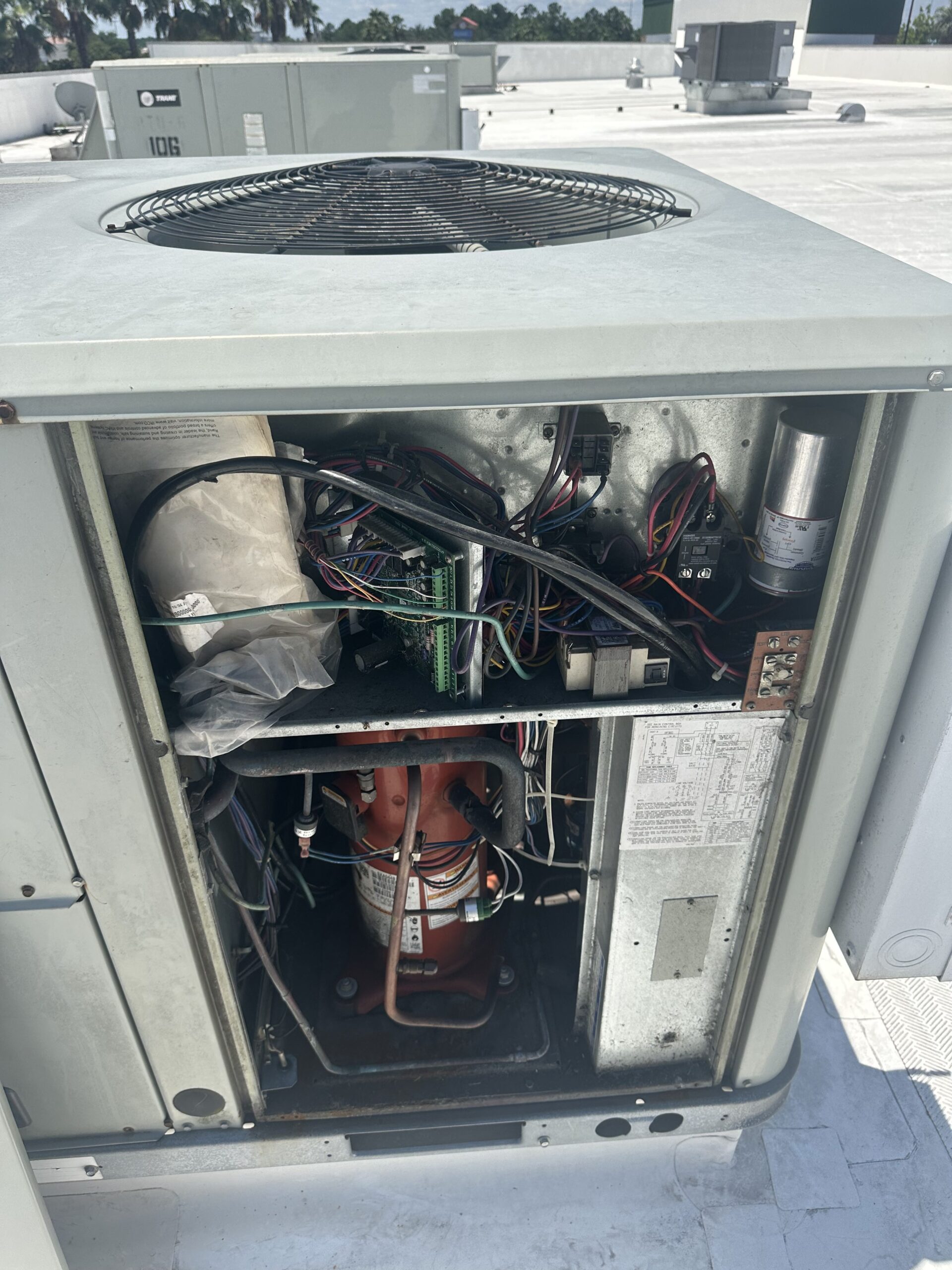 A technician inspects the internal components of an outdoor unit during a standard HVAC contractor visit.
