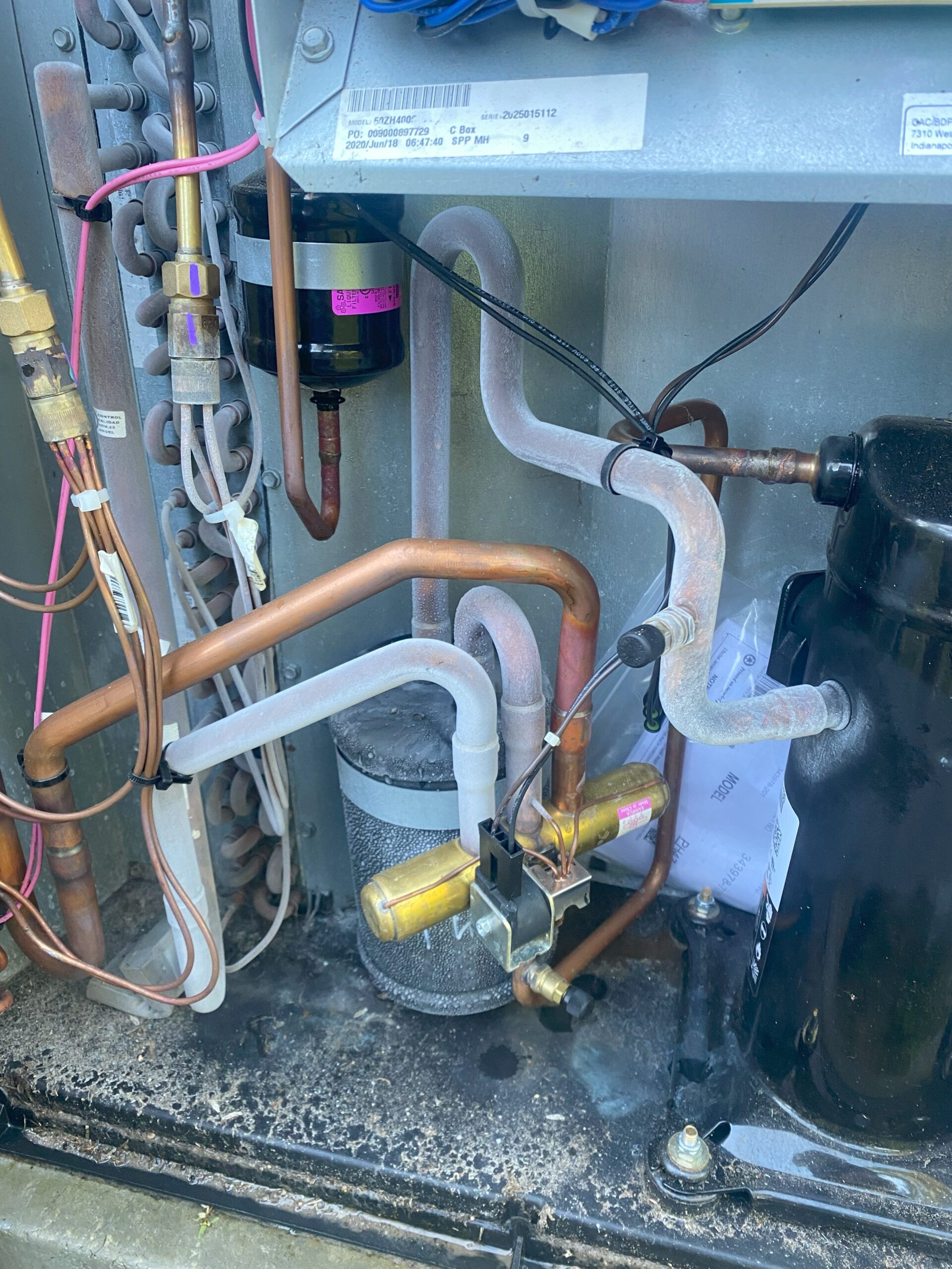 An HVAC contractor is inspecting the wiring and refrigerant lines to ensure the system provides optimal cooling and dehumidification.