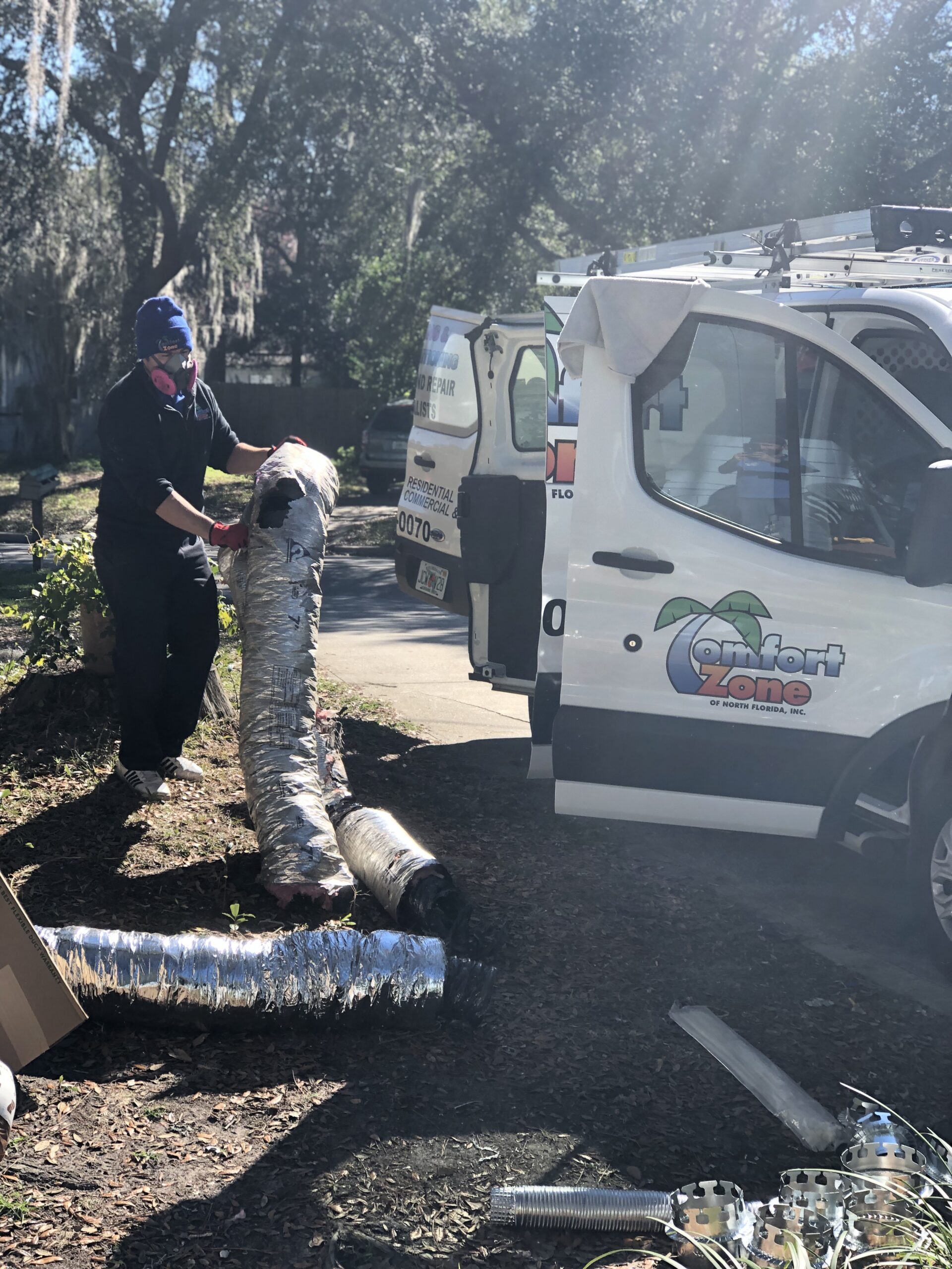 Comfort Zone of North Florida Inc. experts using high-powered vacuum equipment to remove debris during a residential duct cleaning.