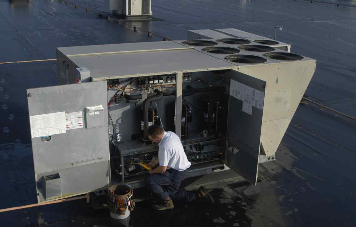 A technician performs Commercial Maintenance on a large rooftop HVAC unit.