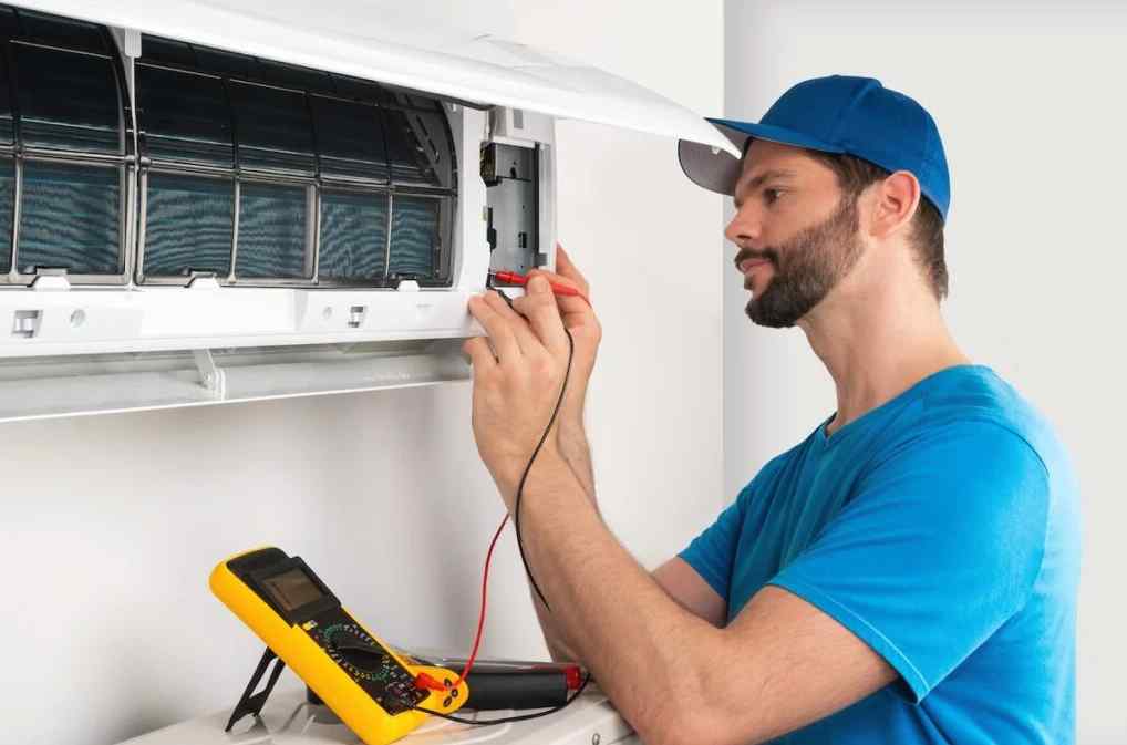 A specialized HVAC technician uses diagnostic tools to examine the electrical components of a commercial AC unit.