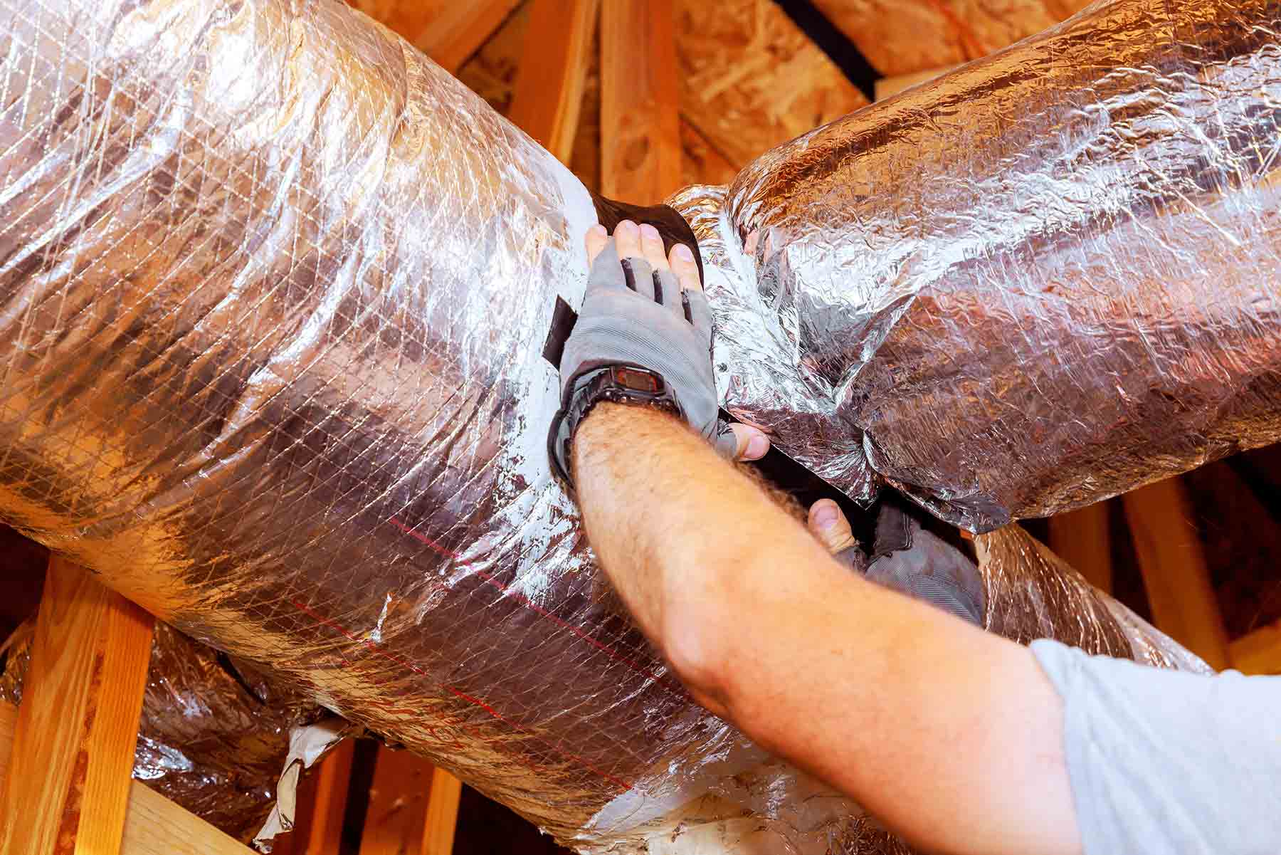homeguide-air-duct-sealing-cost-technician-applying-sealing-tape-on-insulated-ductwork homeguide-air-duct-sealing-cost-technician-applying-sealing-tape-on-insulated-ductwork
