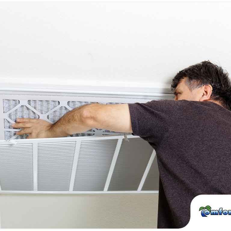 Man replacing the filter in a ceiling air conditioning unit.