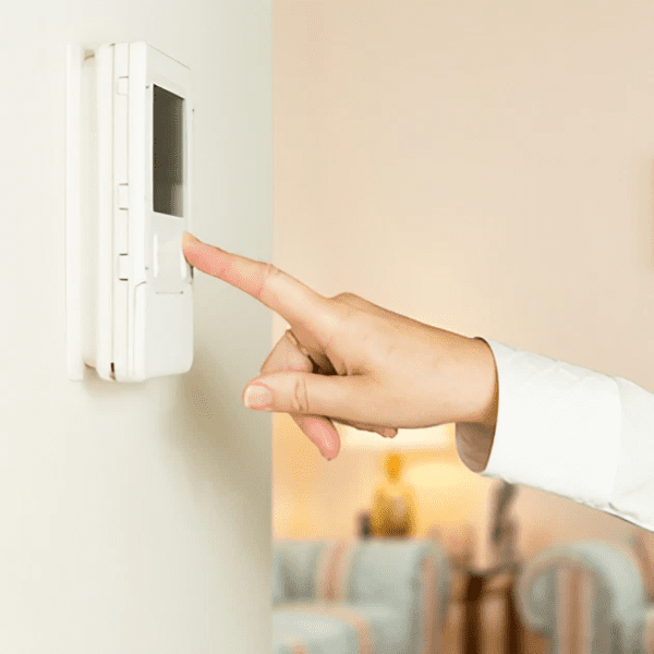 A person is adjusting the residential digital thermostat on an air conditioner to control the temperature