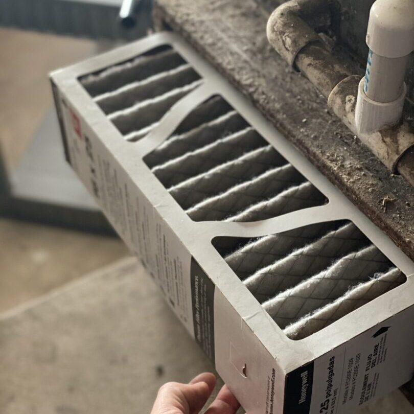 A person replacing a dirty air filter in an hvac system, highlighting the contrast between the old clogged filter and the new clean one.