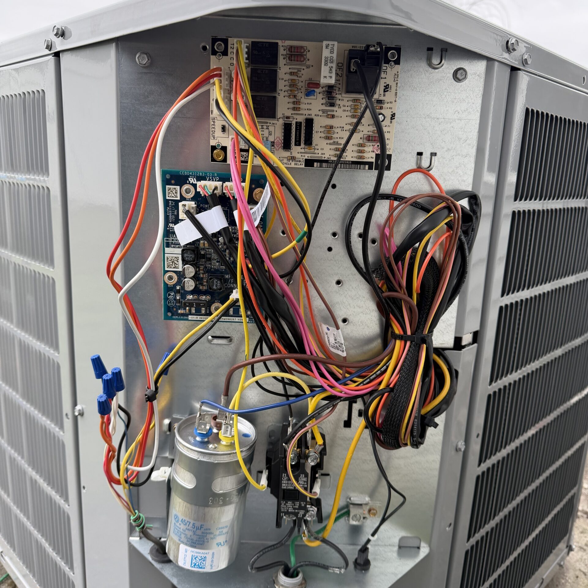 Inside the electrical panel of an air conditioning unit with a defrost control board, capacitor and contactor.