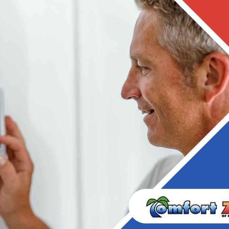 Middle-aged man adjusting a digital thermostat on a wall, smiling, with a business logo in the corner.