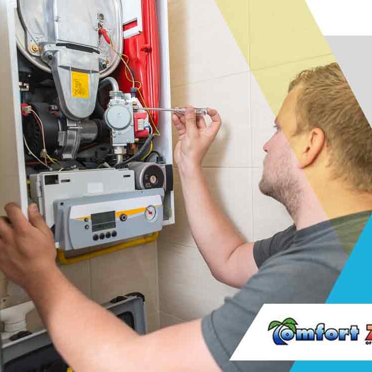A technician repairing a gas boiler while using a screwdriver, with the company logo "comfort zone" visible in the corner.