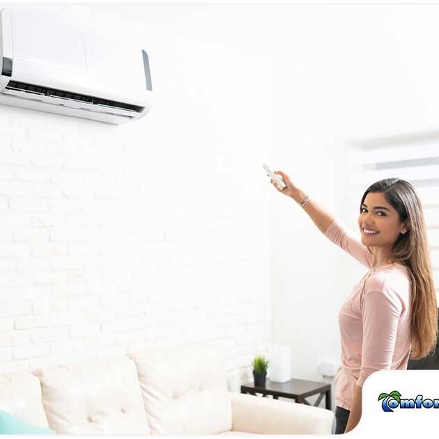 A woman smiling while using a remote control to operate an air conditioner in a bright, modern living room.