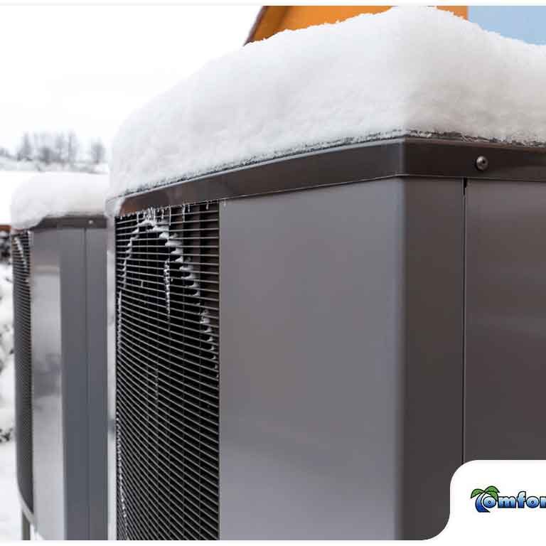 Snow-covered outdoor hvac units outside a residential building in winter.