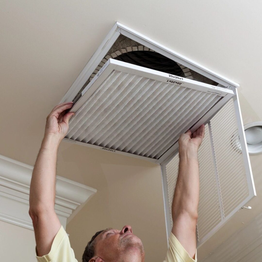 A man is holding an air filter up to the ceiling. A man is holding an air filter up to the ceiling.