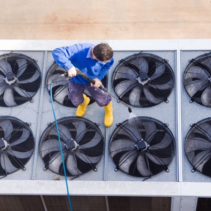 An HVAC professional cleaning an air conditioning unit to ensure optimal performance and efficiency An HVAC professional cleaning an air conditioning unit to ensure optimal performance and efficiency