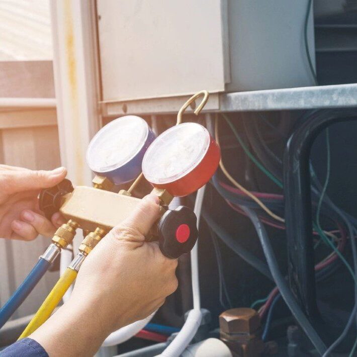 An HVAC technician working on a commercial air conditioning unit, performing maintenance or repairs.